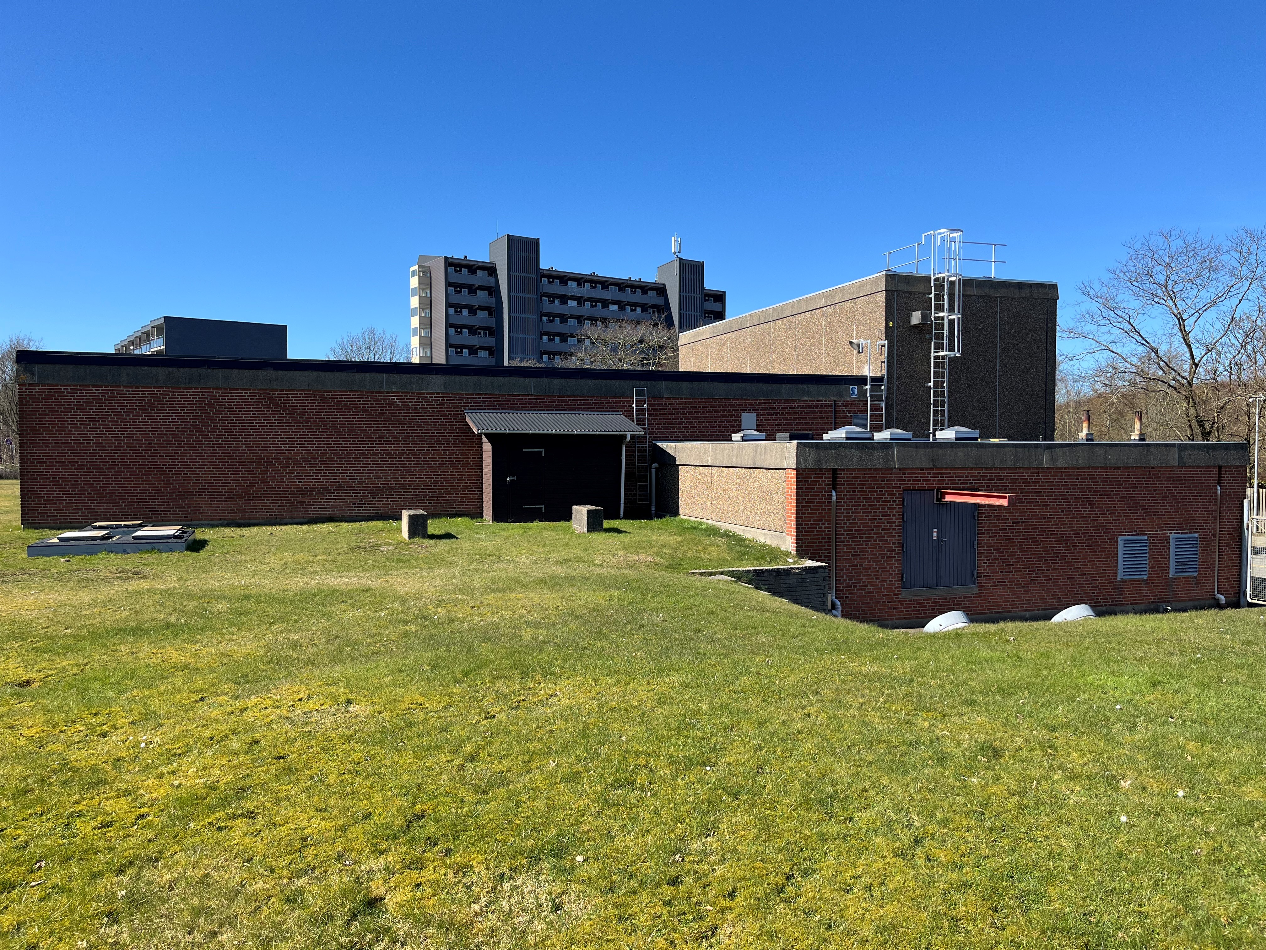 Vognsbøl vandværk - Rød bygning med hvidt højhus i baggrunden.